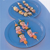Grillspieße mit Huhn, Shrimps, Ananas und Kumquats auf blauen Tellern