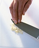 Close-up of man's hand crushing garlic with knife