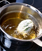 Basil wrapped in tempura being deep fried in vegetable oil
