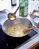 Risotto being prepared by cooking rice in vegetables and wine