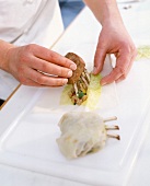 Close-up of a man's hands filling filo pastry with rack of lamb