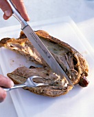 Close-up of a man's hands cutting a duck with knife