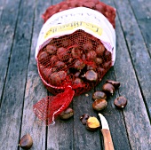 A sack of chestnut and some chestnuts spilled on wooden table