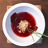 Beetroot soup with chives and riebele in white bowl