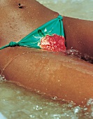 Teilansicht: braungebrannte Frau im Bikinihöschen mit Erdbeerendruck
