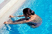 Woman with dark hair performing water aerobics in pool