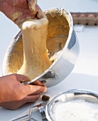 Close-up of man vigorously stirring spatzle in a bowl