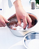 Close-up of kidneys being vigorously massaged with salt to make it soft