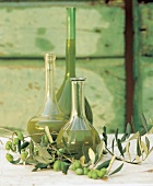 Flaschen mit Olivenöl, grüne Oliven 