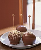 Drei Liebesäpfel m. Schokoladenüberzug auf weißem Teller