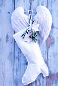 Close-up of white Christmas stocking and pair of angel wings on wooden wall