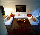 Wohnraum mit weißer Sofagruppe + braunem Cotto-Fliesenboden