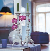 2 weiß lasierte Barock Kerzenständer vor Kugelvase mit Orchidee