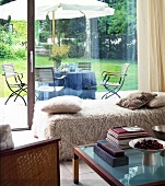 Blick aus dem Wohnzimmer auf die Terrasse mit Tisch + Sonnenschirm