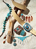 Close-up of jewellery and belt buckle in silver and turquoise on sand