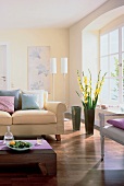 Teilansicht eines Raumes in hellen Farben: Sofa, Bodenvase m. Gladiolen