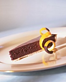 Piece of chocolate tart with candied orange peel on plate