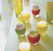 Farbige Eierbecher aus Glas mit Kerzen in offenen Eierschalen