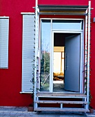 Haustür mit Fensterumrandung und Pergola, rote Fassade