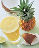 Glas frischer Ananassaft, Ananas, Kokosnuss im Hintergrund