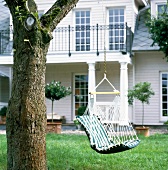 Striped swing seat hanging on the tree in front of house