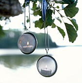 Teelichter in Teesieb hängen als Windlichter im Baum