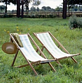 Two folding chairs with striped fabric in the middle of green field