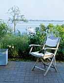 Stuhl auf einer Terrasse, im Hintergrund Ostsee