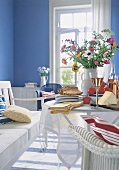 Blau-weißes Zimmer mit Käse + Wein + Sommerblumen auf dem Tisch