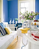 Blau-weißes Zimmer mit Kuchengedeck + Sommerblumen auf dem Tisch