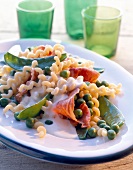 Close-up of fusilli in cream sauce with prosciutto and peas on plate