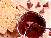 Dipping triangle shaped pieces of cake in chocolate syrup with fork