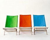 Three folding chair made of beech wood with green, orange and blue linen cover