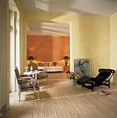 Blick in Zimmer, Holzfußboden, Wände in ockergelbem Farbton, 3 Sessel