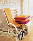 Stack of cushions and fringed scarf on bench
