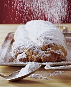 Marzipan- Stollen wird mit Puderzucker bestreut, close up