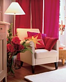 Sessel vor rotem Vorhang, rötliche Kissen Stehlampe Bodenvase Weihnacht