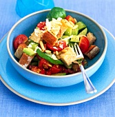 Bread salad with tomatoes, basil and pine nuts in bowl with fork