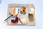 Breakfast table set with bread rolls, cheese, sausage cake, coffee on table mat
