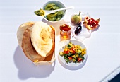 Breakfast table set with avocado cream, fig, date, pita bread and salad on table