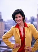 Portrait of young woman with dark hair wearing yellow blazer over red blouse, smiling