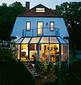 View of illuminated starter house with winter garden at dusk