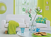 Weißes Sofa mit Kissen, Wolldecke und Wänden in Grün- Tönen