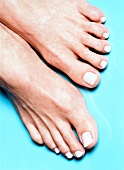 Close-up of woman's feet wearing bright nail paint against blue background