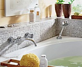 Armaturen an einer Badewanne, Fliesen in Mosaik-Optik