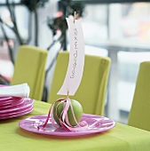 Green apple with name card on skewer on pink plate