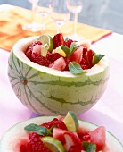 Obstsalat mit Erdbeeren, Limone und Minzblättchen in einer halben Melone