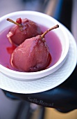 Close-up of two pears in red wine in white bowl