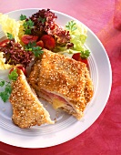 Cordon bleu with filling of ham and cheese and salad dressing on white plate