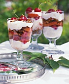 Glass goblets of cherries, apricots, cream and pieces of amarettini biscuits